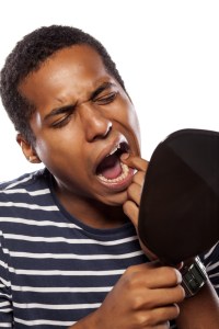 man checking his teeth in a mirror